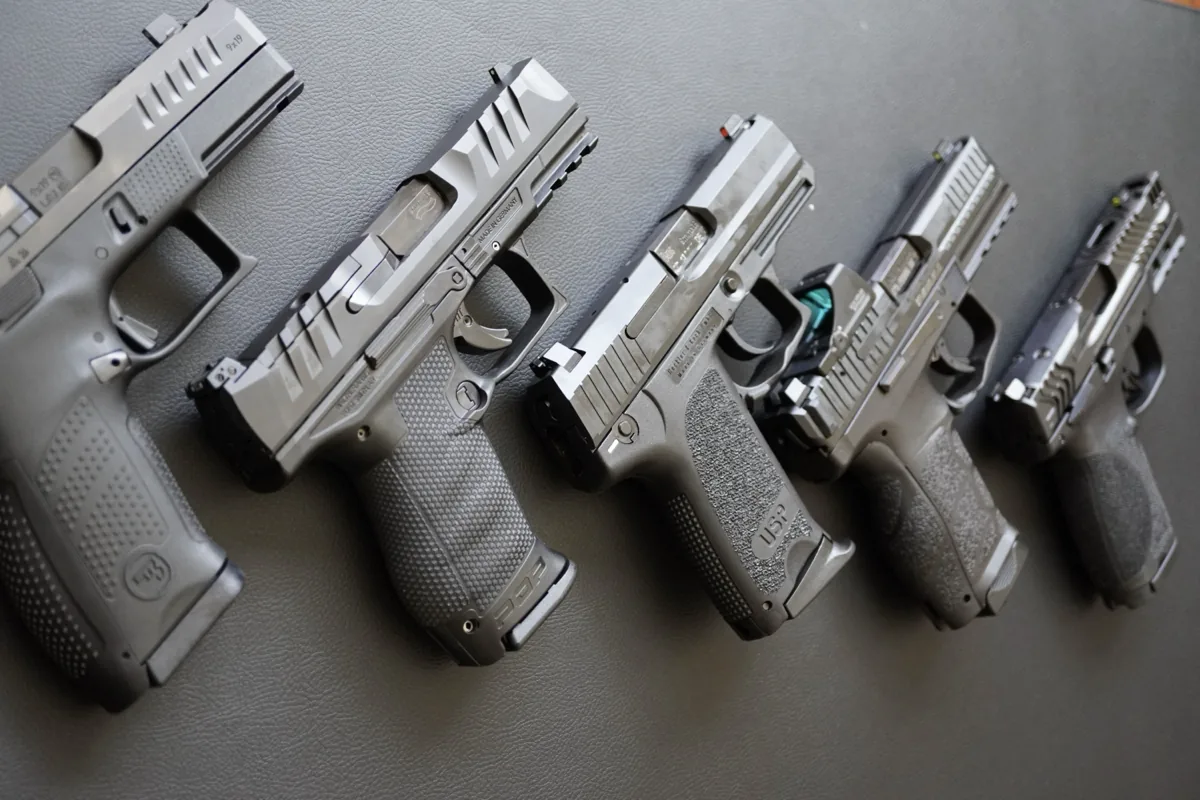 Five 9mm pistols lined up on a leather mat: CZ P10c, Walther PDP, HK USP Compact, and two more compact pistols