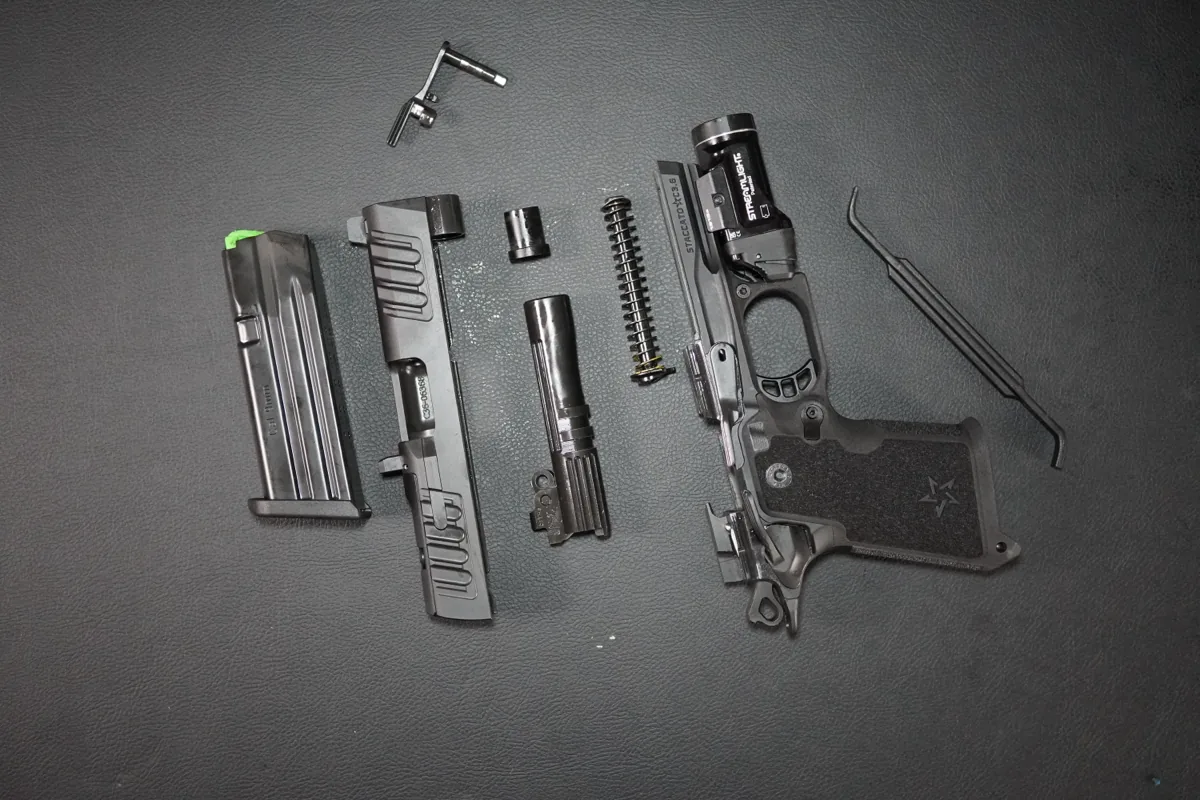 Staccato HD 3.6 fully field stripped on a leather mat: magazine, slide, barrel components, recoil spring assembly, frame, and slide stop