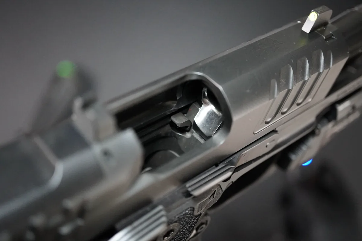 Looking down into the ejection port of a Staccato HD 3.6 at the interior face of the slide stop, visible through the takedown window
